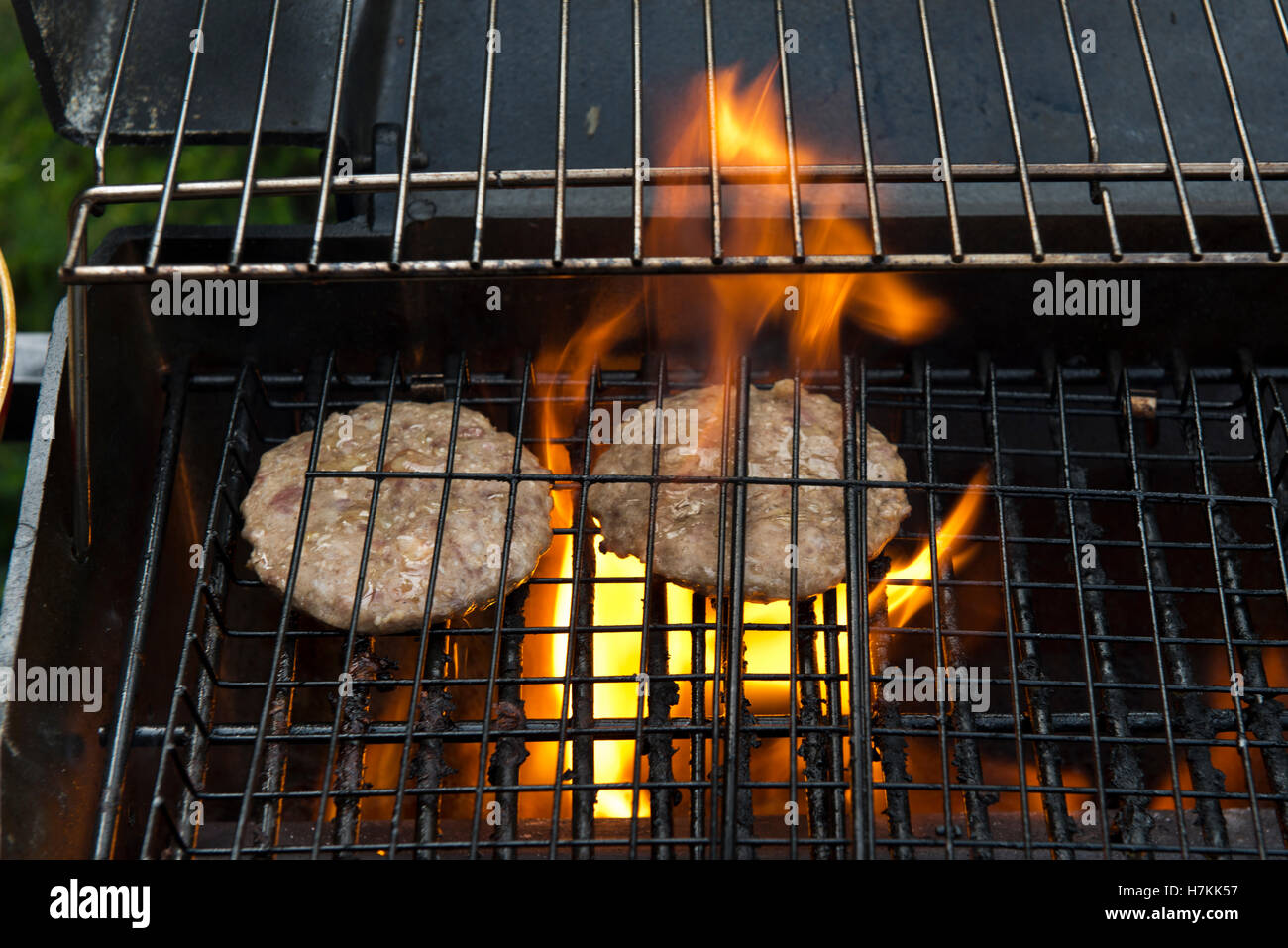 Due beefburgers cottura su un barbecue Foto Stock
