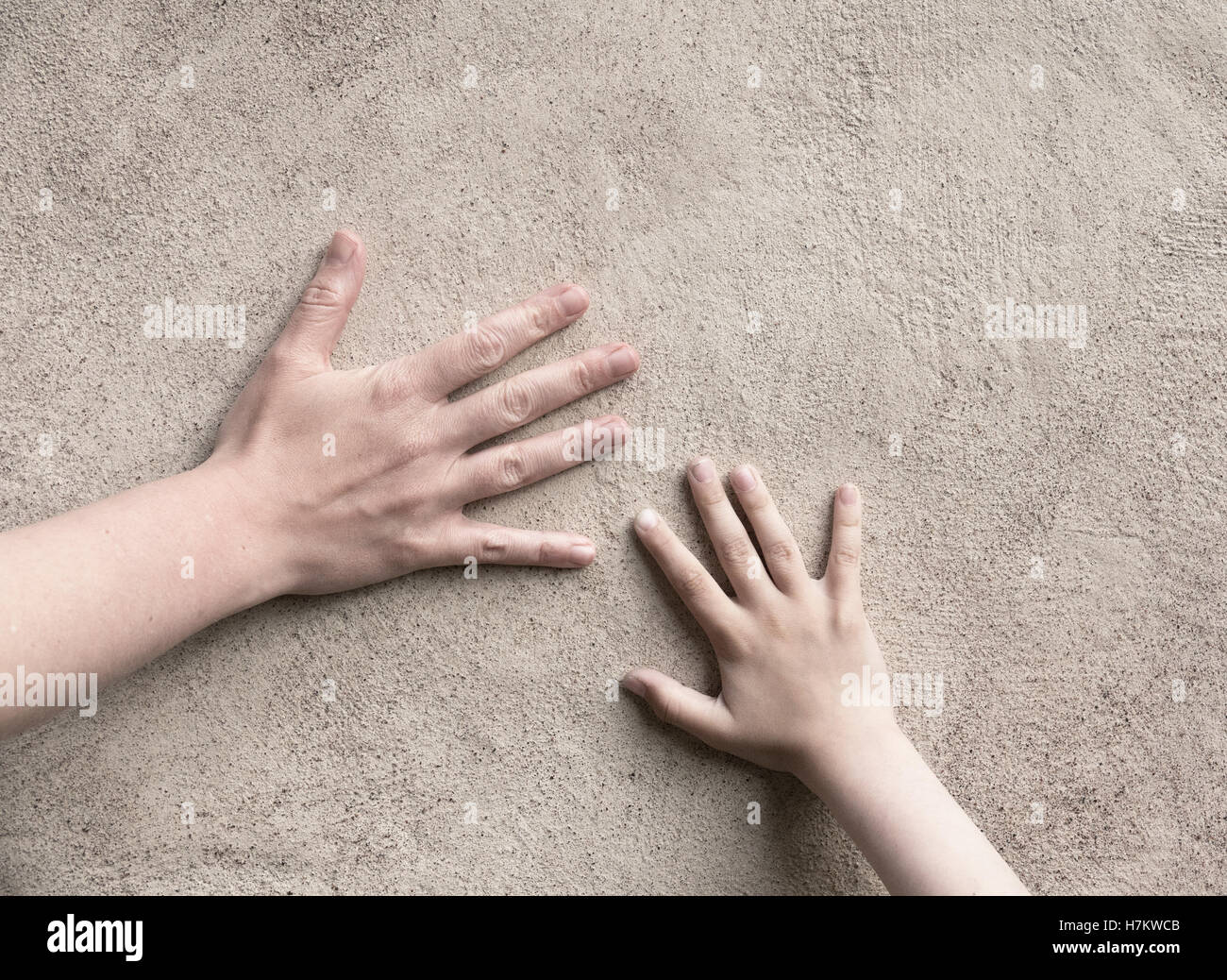 Due mani di connessione. Adulto e bambino mano soddisfare, toccando una parete. Immagine concettuale del collegamento tra genitore e bambino. Foto Stock