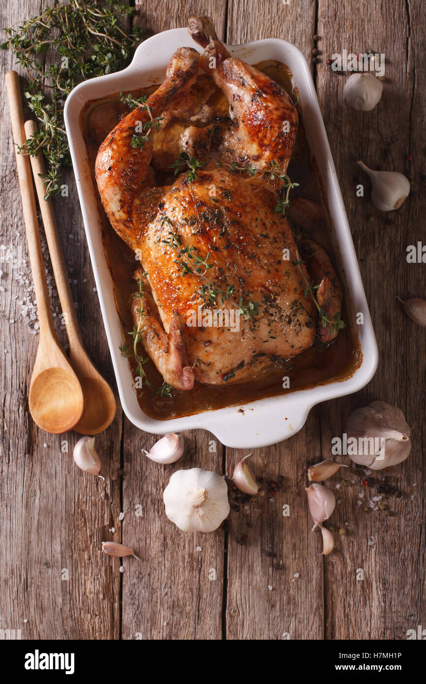 Cibo francese: pollo con quaranta spicchi di aglio nel piatto di cottura e ingredienti di close-up sul tavolo. vista verticale fro Foto Stock