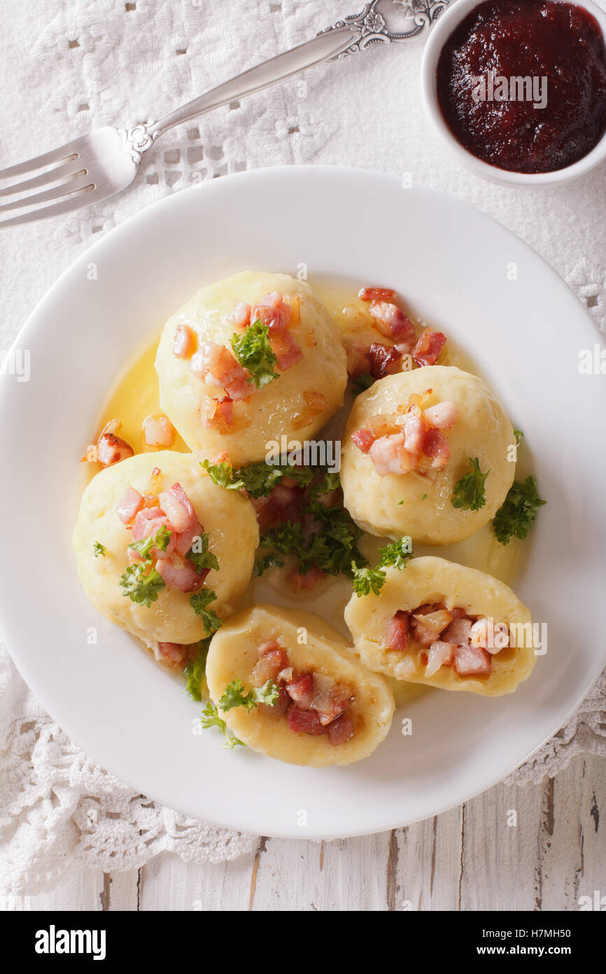 Gli gnocchi di patate ripiene con prosciutto e pancetta e cipolla close-up su una piastra. vista verticale da sopra Foto Stock