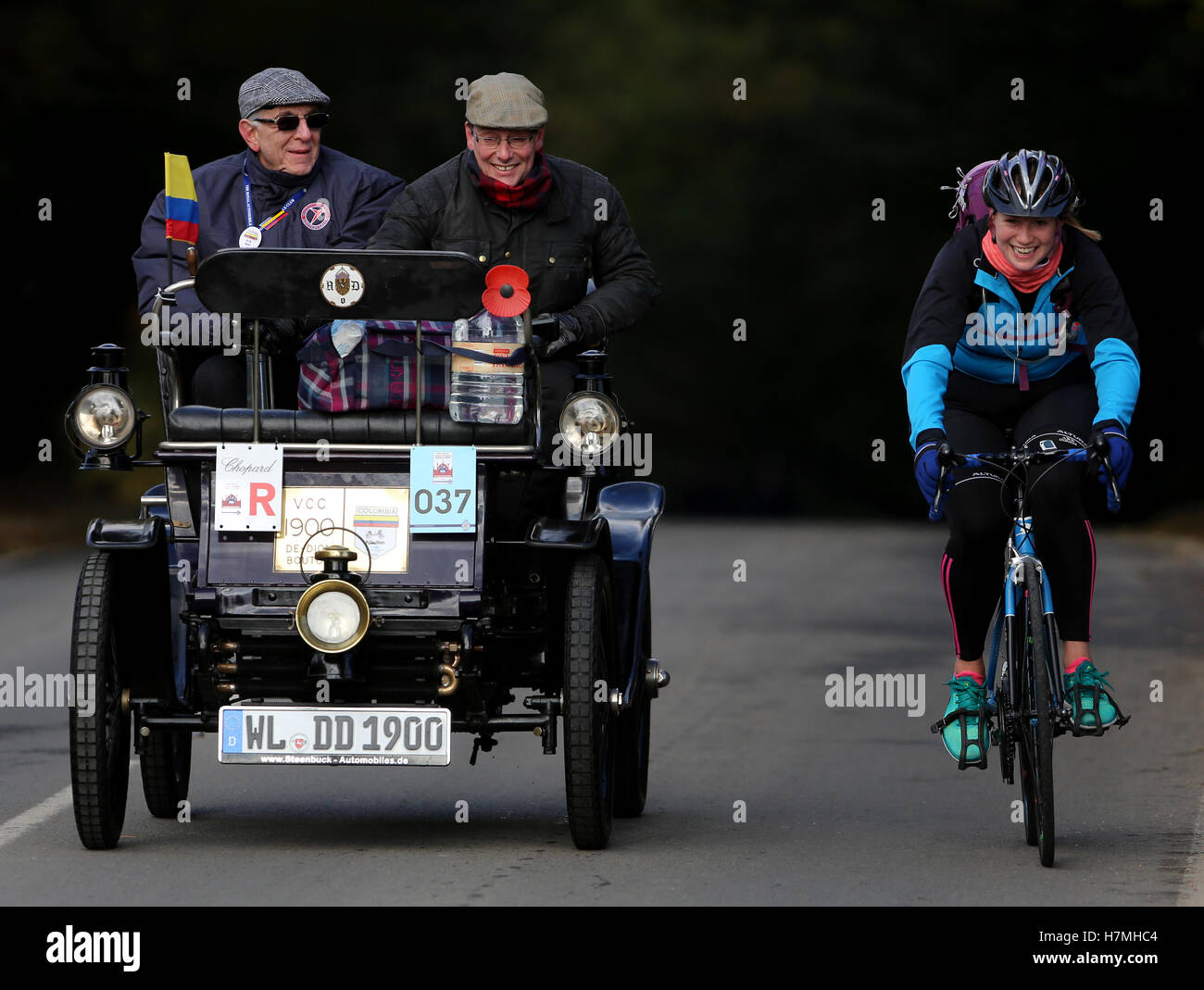 I partecipanti al Bonhams Londra a Brighton Veteran Car Run sono sopraffatti da un ciclista come essi head up Holmsted collina vicino a Crawley Sussex. Foto Stock