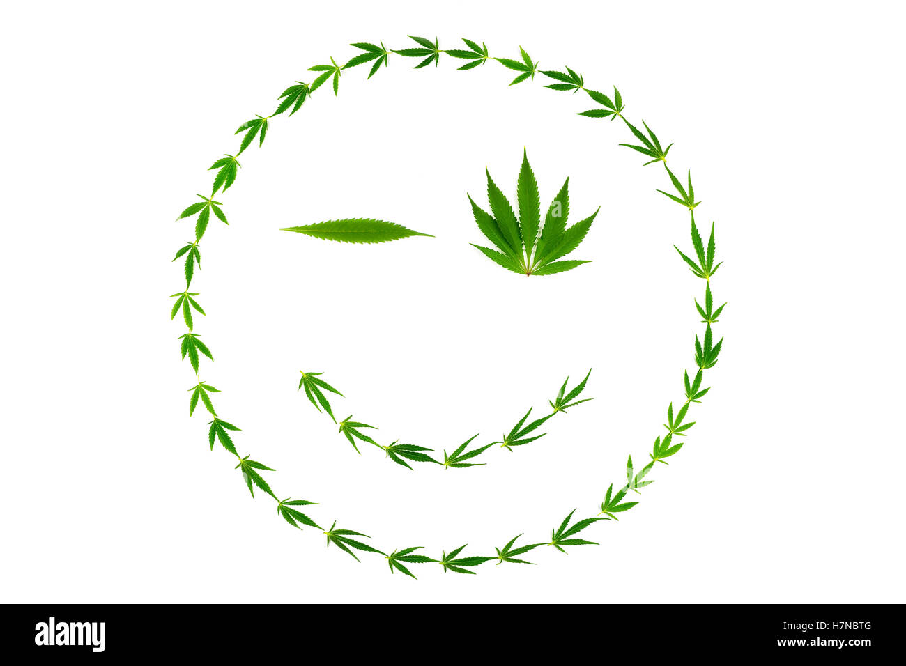 Winking volto sorridente fatta di foglie di cannabis isolati su sfondo bianco Foto Stock
