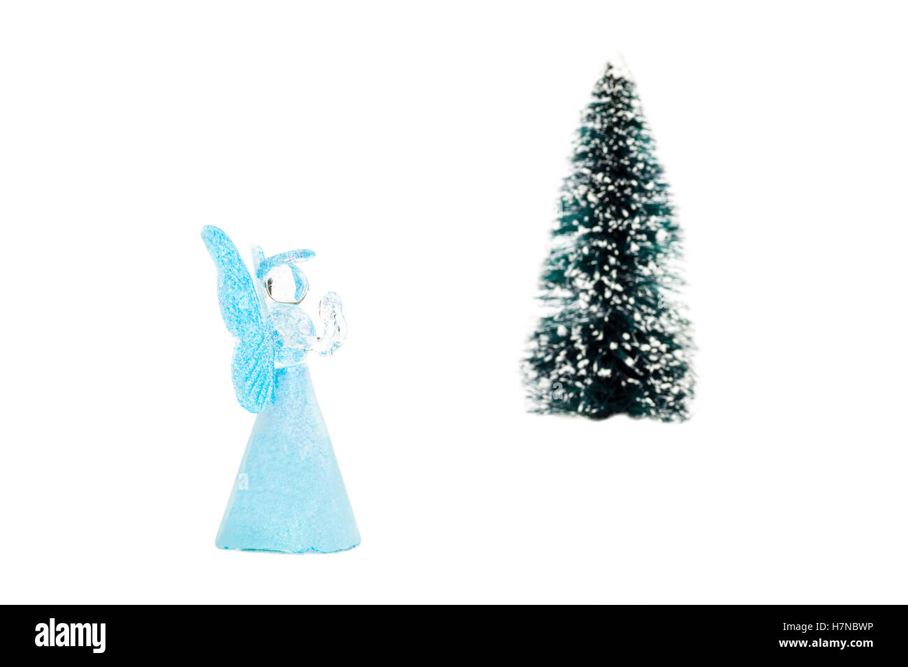 Vetro blu angel pregando vicino albero di natale su sfondo bianco Foto Stock