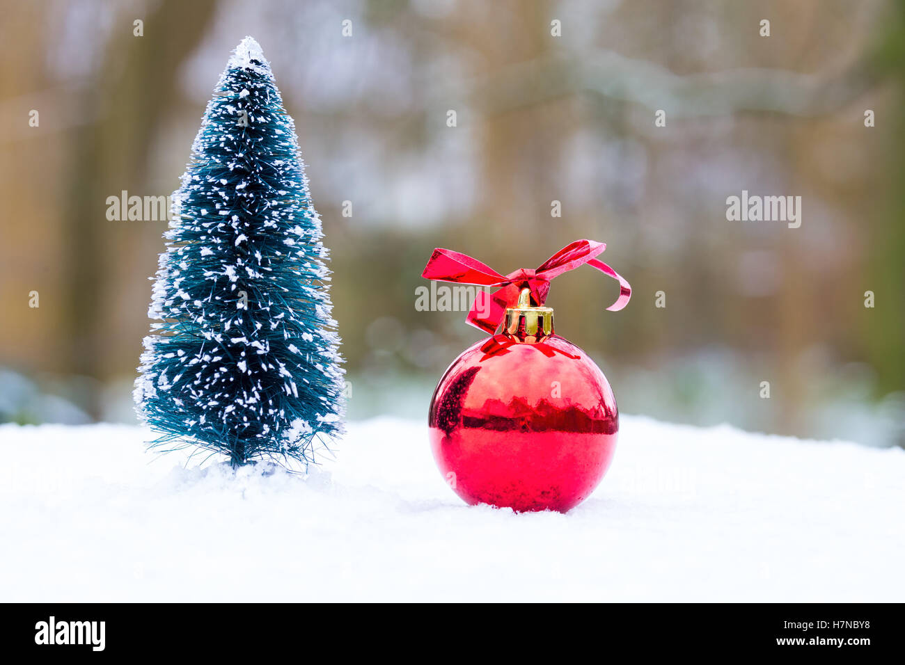 Piccolo albero di natale e la sfera rossa al di fuori nella neve Foto Stock