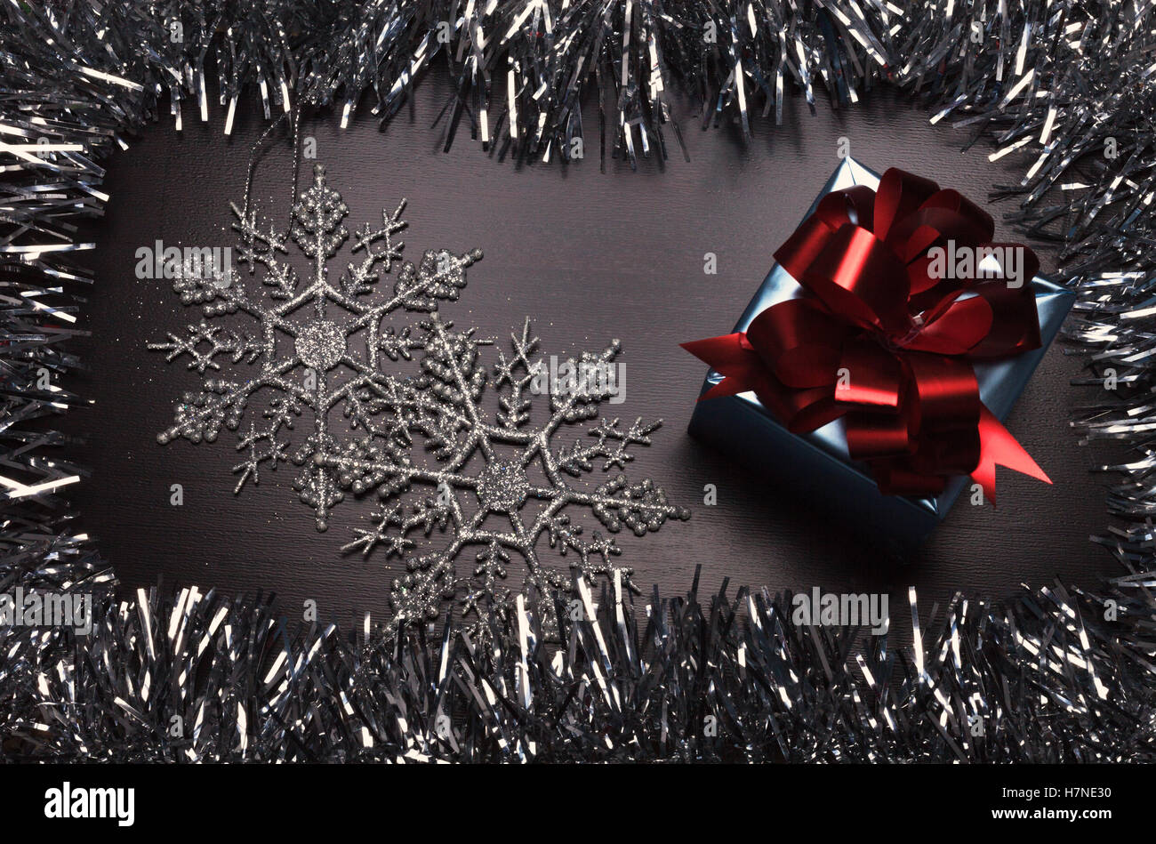 Confezione regalo con i fiocchi di neve su sfondo di legno con illuminazione scarsa Foto Stock