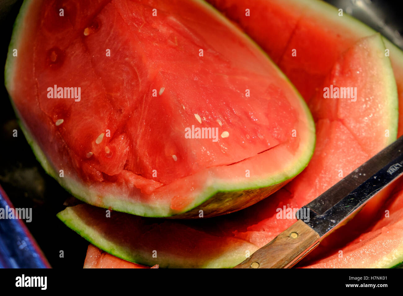Porzioni di fresca anguria seedless essendo tagliato su un bancone cucina e lavello. Foto Stock