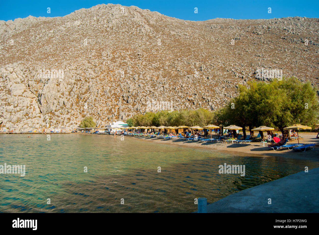 Spiaggia di Saint Nicholas bay su symi con ombrelloni e lettini Foto Stock