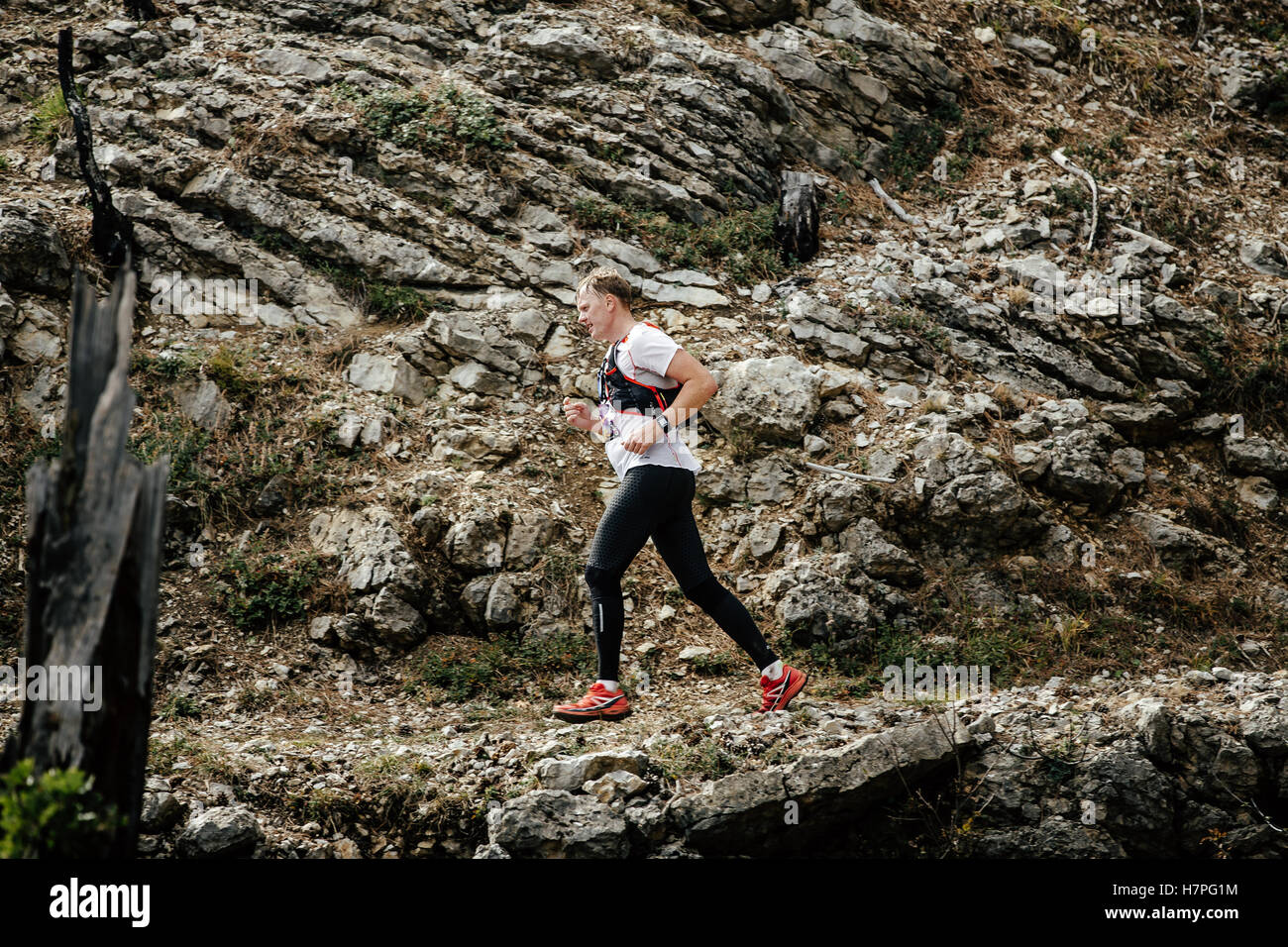 Giovani runner viene eseguito su un sentiero di montagna in pietra di sfondo rocce durante la Crimea maratona di montagna Foto Stock