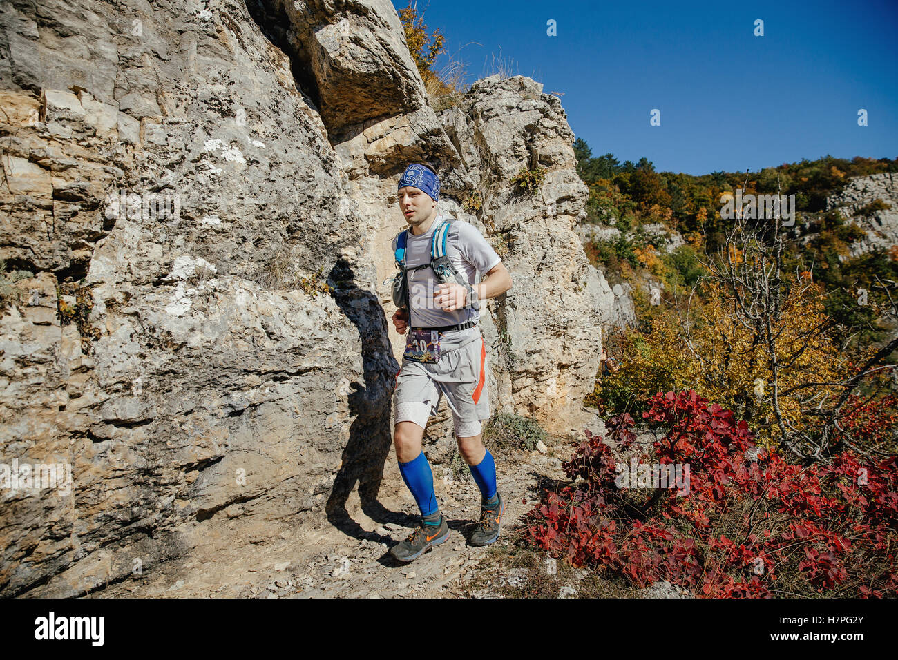 Runner maschio di correre su una pista accanto a rocce e foresta autunnale durante la Crimea maratona di montagna Foto Stock