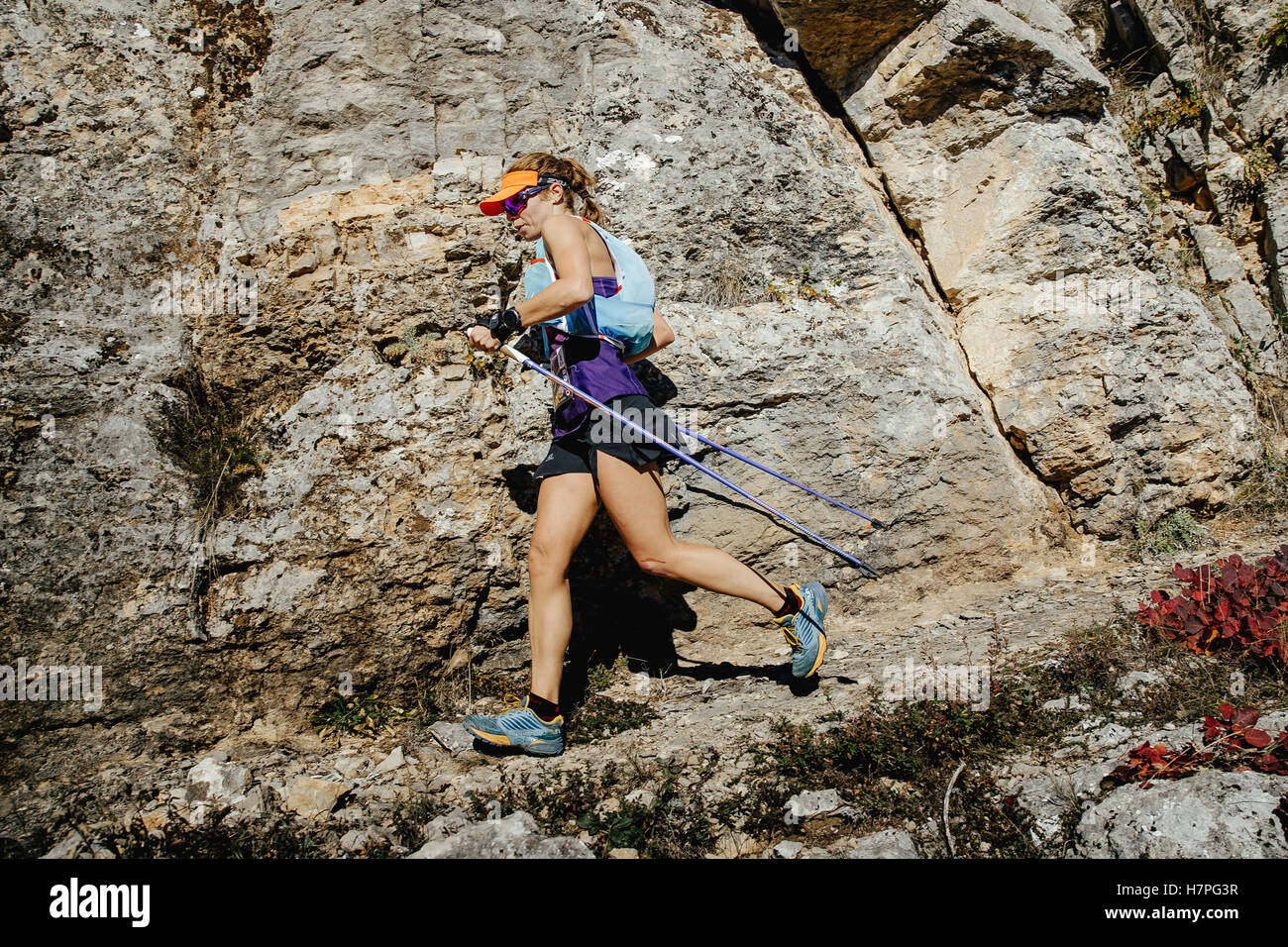 Donna runner con bastoncini da nordic walking trail in esecuzione sullo sfondo di rocce durante la Crimea maratona di montagna Foto Stock