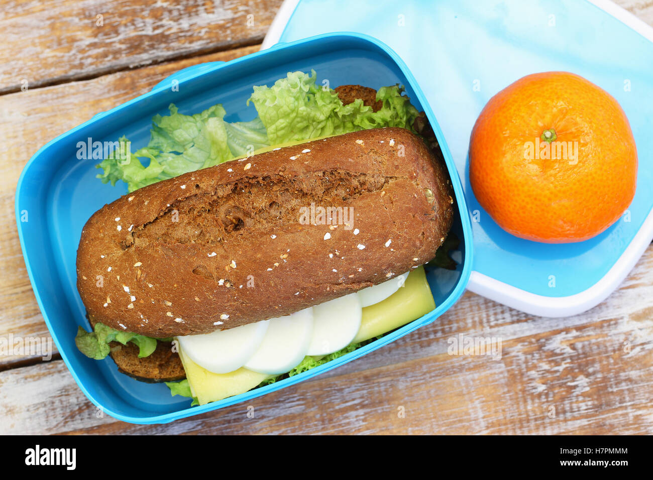 Scatola di pranzo contenenti marrone Rotolo di pane con formaggio, uovo sodo, lattuga e clementine Foto Stock