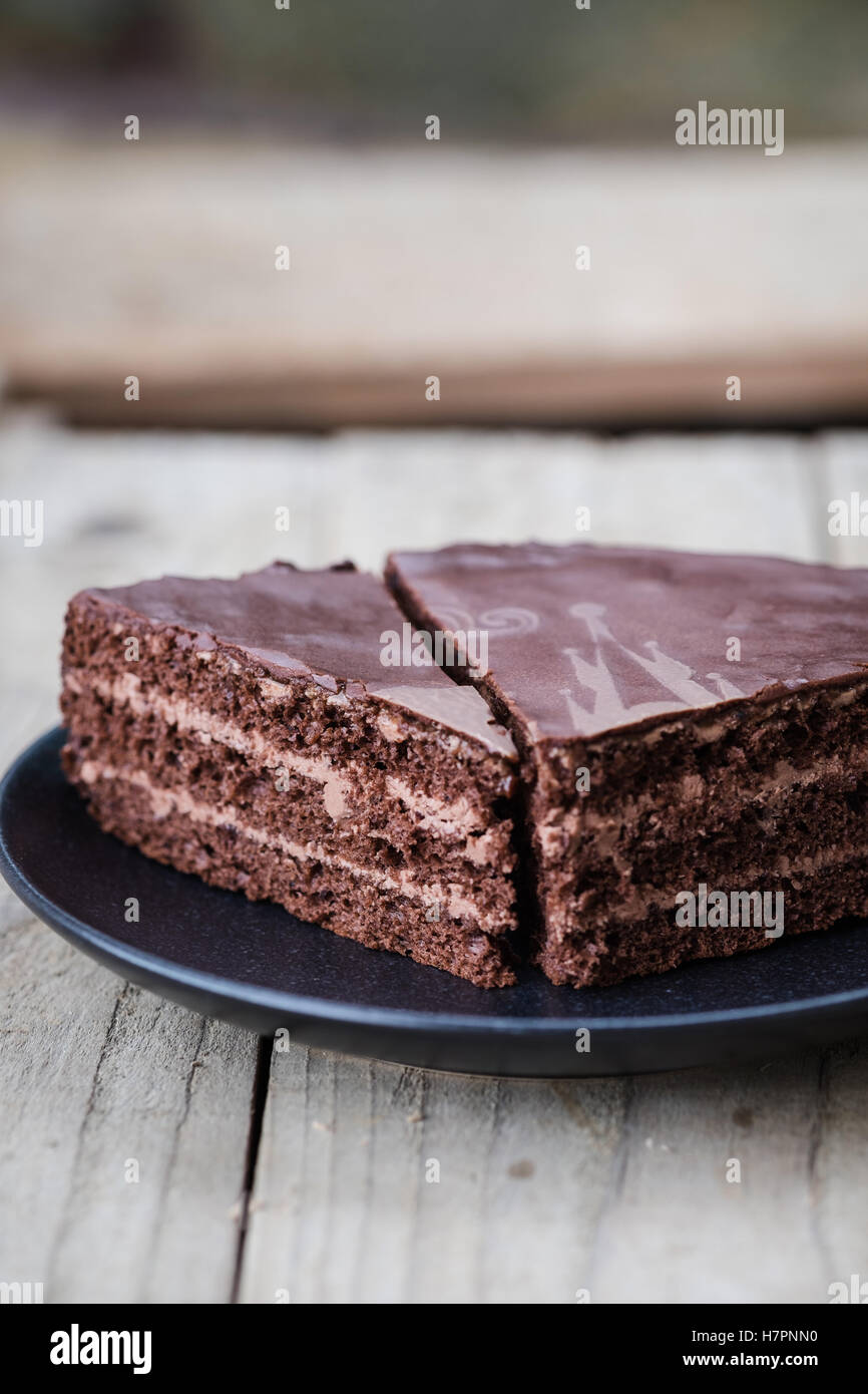 Taglio di strato di cioccolato torta con crema di cioccolato e smalto su una piastra di scuro. Sfondo di legno. Close up Foto Stock