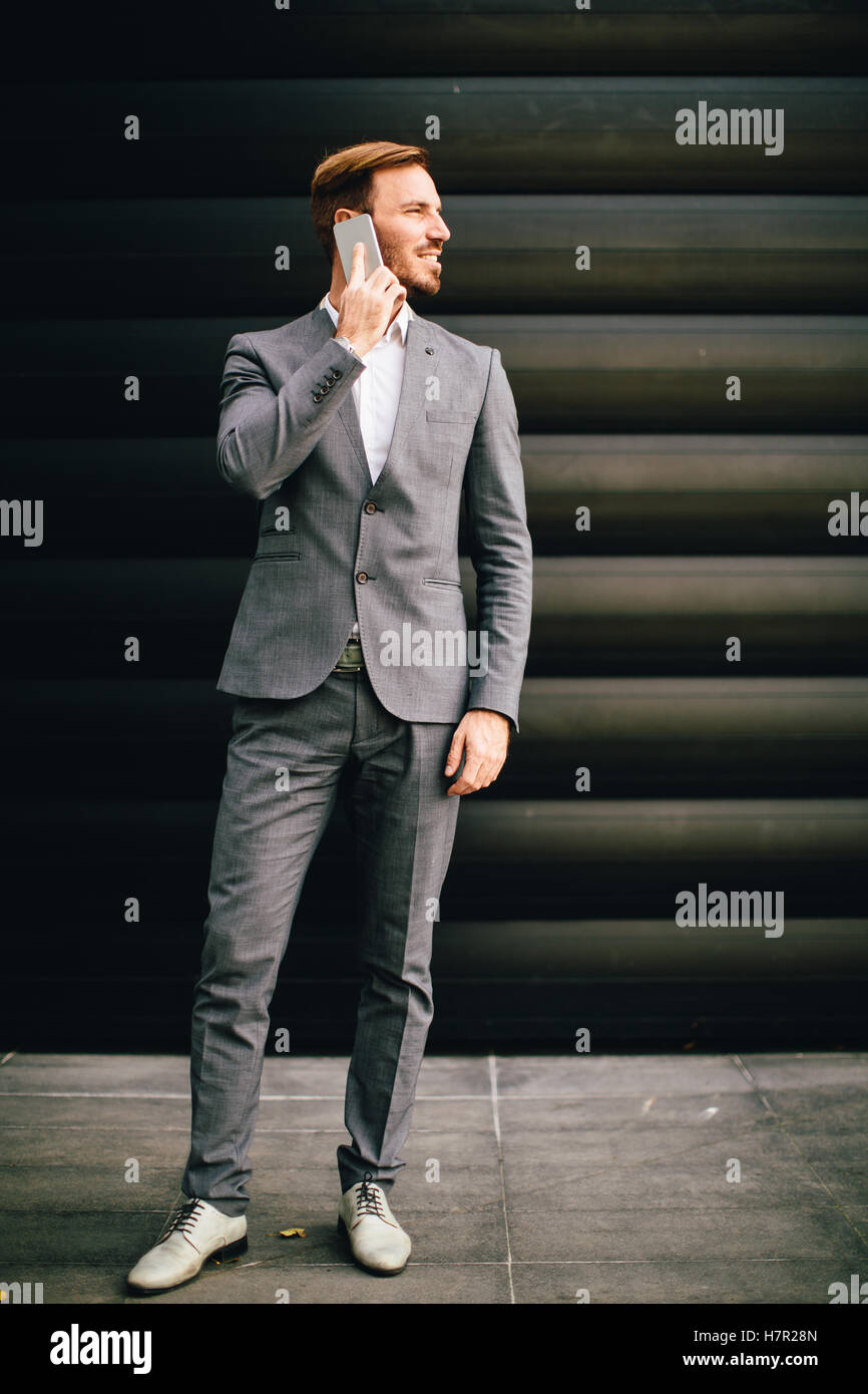 Imprenditore con un telefono dal muro nero Foto Stock