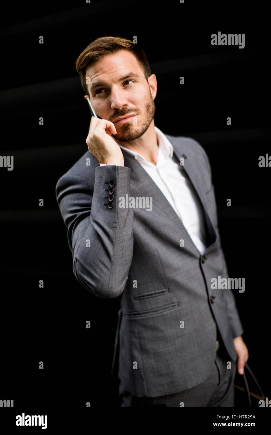 Imprenditore con un telefono dal muro nero Foto Stock