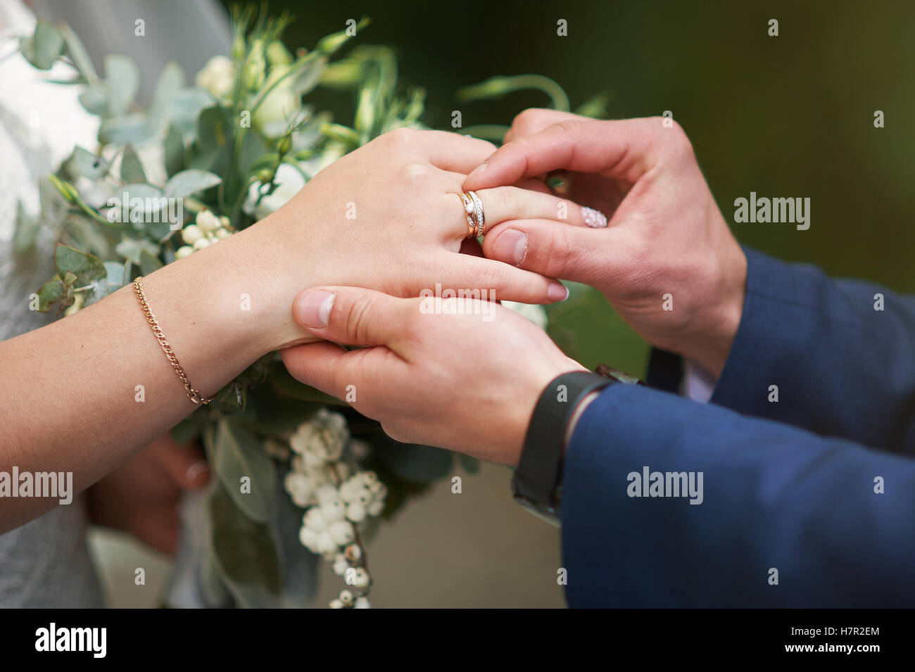 Lo sposo mettendo mano un anello di nozze sul dito della sposa Foto Stock