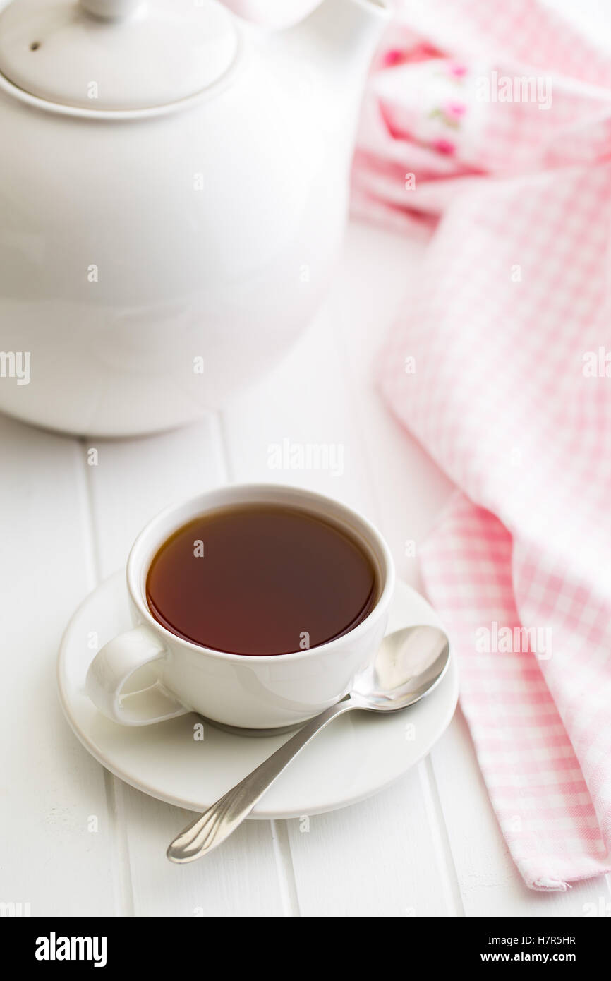 Una tazza di tè nero e teiera sul tavolo bianco. Foto Stock