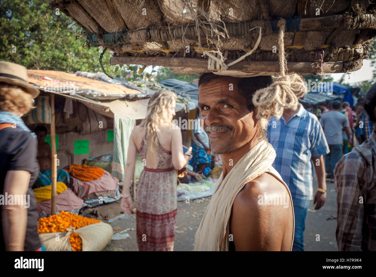 Un facchino che porta un vassoio sul suo capo presso il mercato dei fiori, Kolkata (Calcutta) Foto Stock