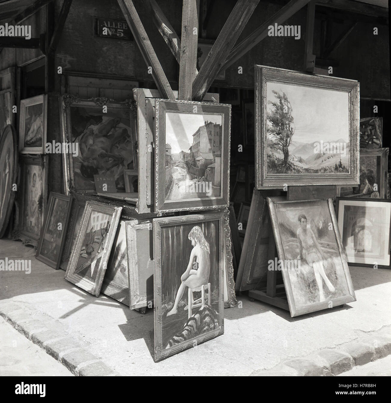 Degli anni Cinquanta, storico, una selezione di cornici e di opere d'arte e quadri ad olio per la vendita a un open-air stallo a un mercato delle pulci Parigino, Parigi, Francia. Foto Stock