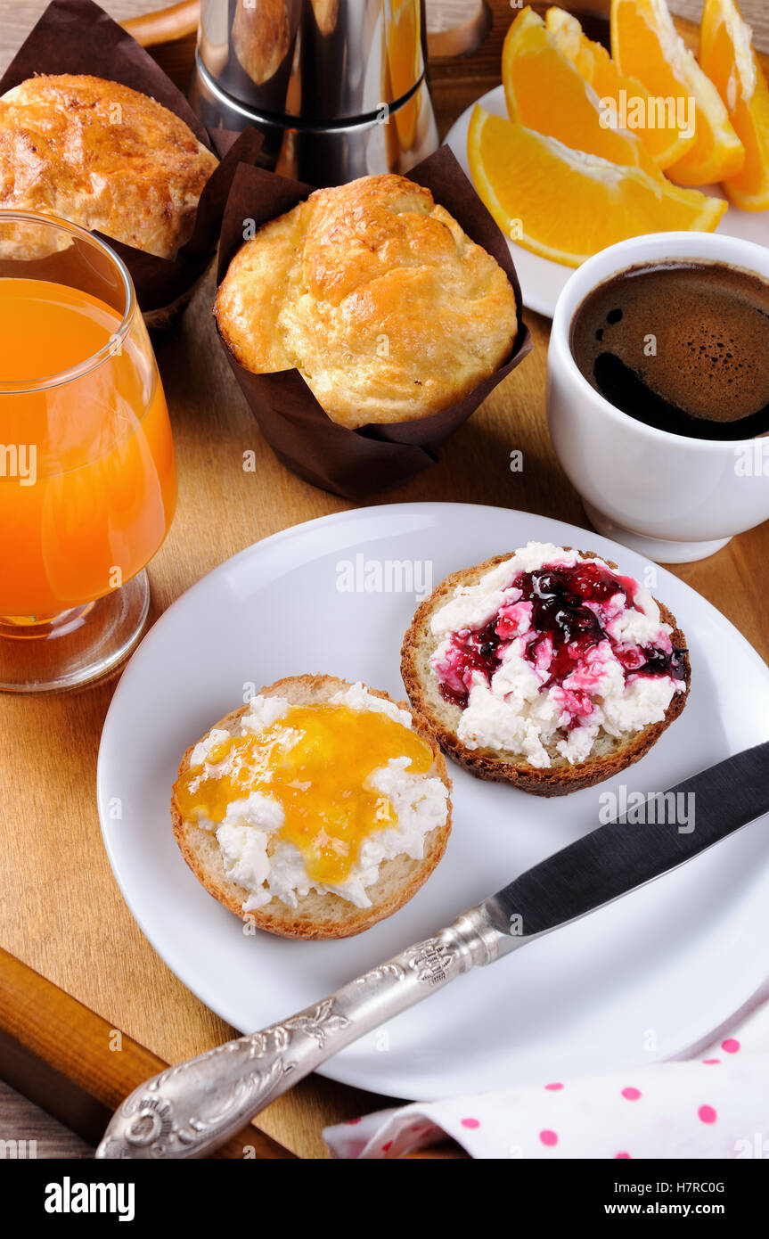 La prima colazione di bun con ricotta arancione e confettura di ciliegie Foto Stock
