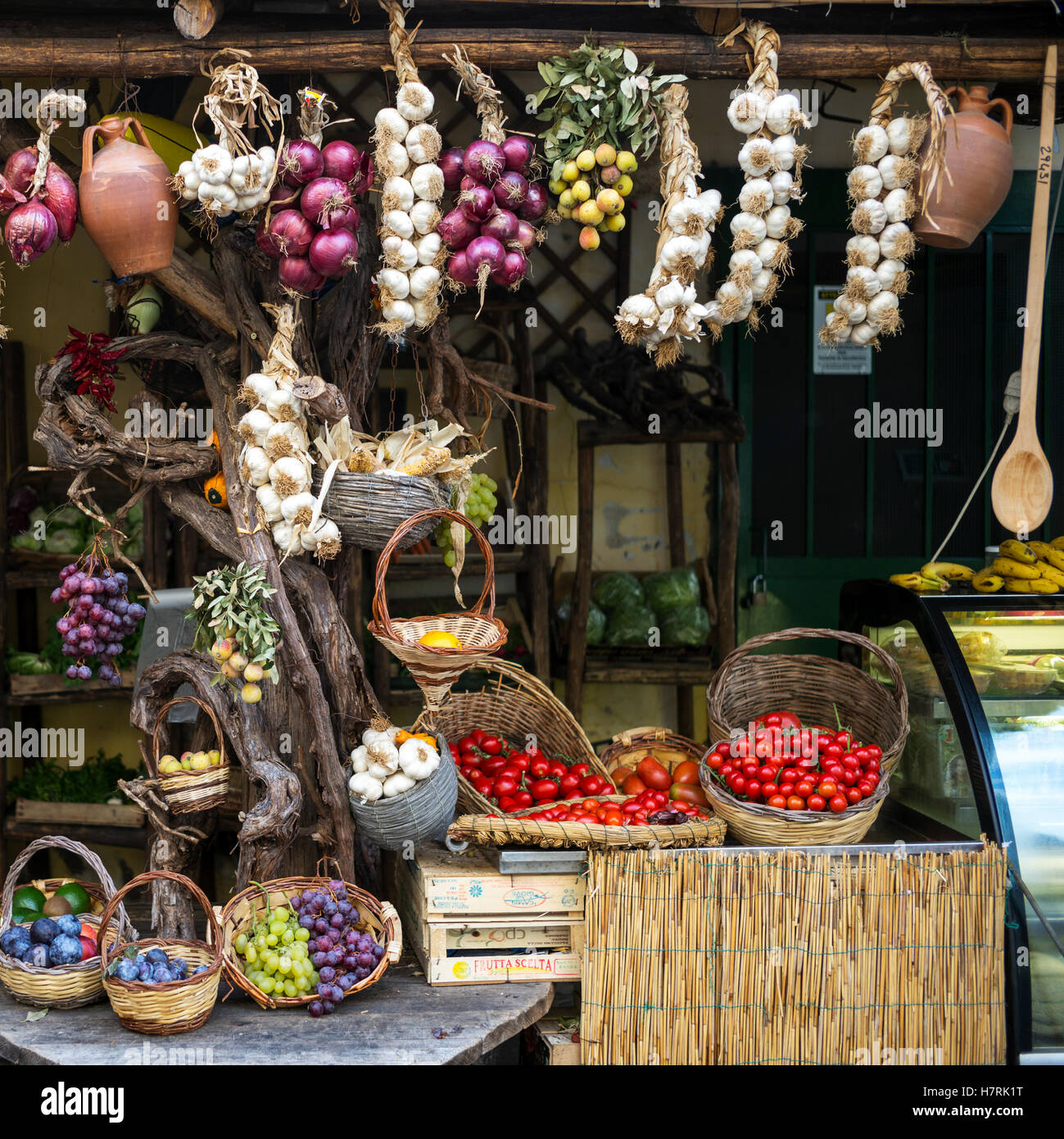 Frutta fresca e verdure compresi appeso aglio e cipolla, sul display per la vendita su un mercato; Ischia, Campania, Italia Foto Stock