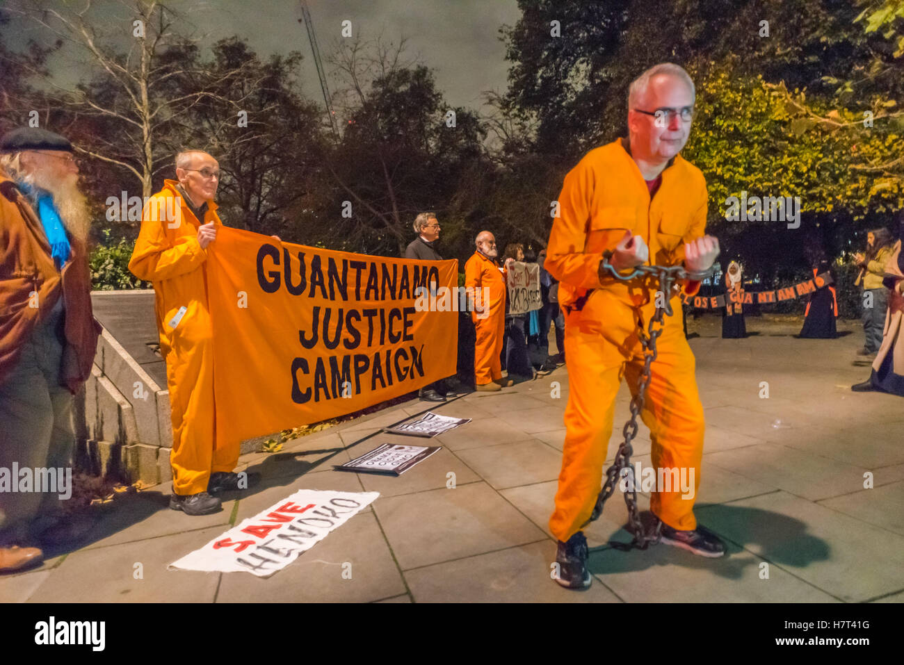 Londra, Regno Unito. 8 novembre 2016. Un uomo da Londra a Guantánamo campagna pone in una tuta arancione e le catene alla protesta che la polizia allontanato dall'ambasciata per chiedere la chiusura di Guantanamo, dove kangaroo "giustizia" persiste con la detenzione indefinita senza processo per coloro che restano in vigore e alimentazione, percosse e brutalità continuare. Credito: Peter Marshall / Alamy Live News Foto Stock