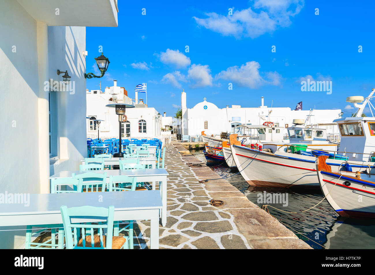 Taverna tavoli e le tradizionali barche da pesca nel porto di Naoussa, isola di Paros, Grecia Foto Stock