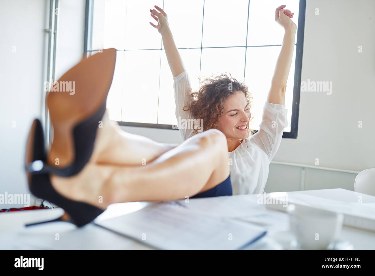 Business donna celebra il suo successo con i suoi piedi fino Foto Stock