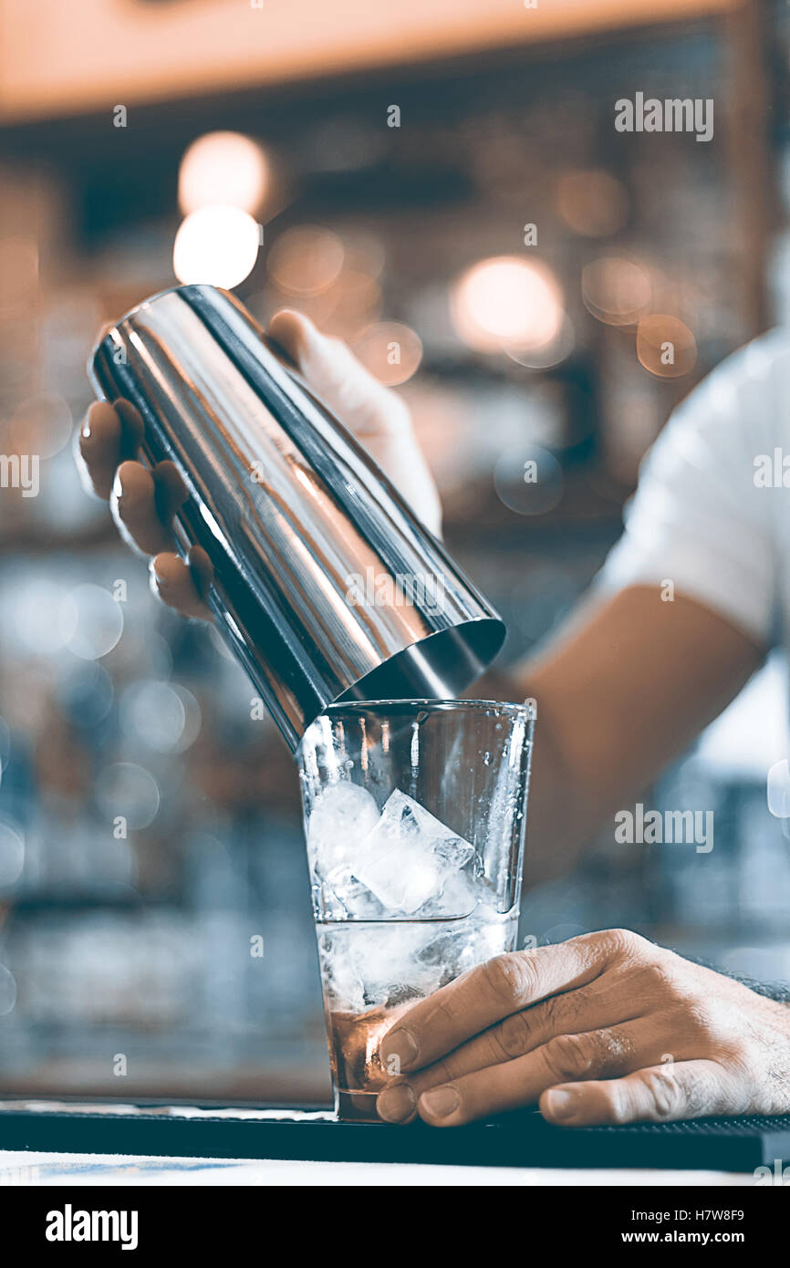 Esperto barman rendendo cocktail al night club shaker. Foto Stock