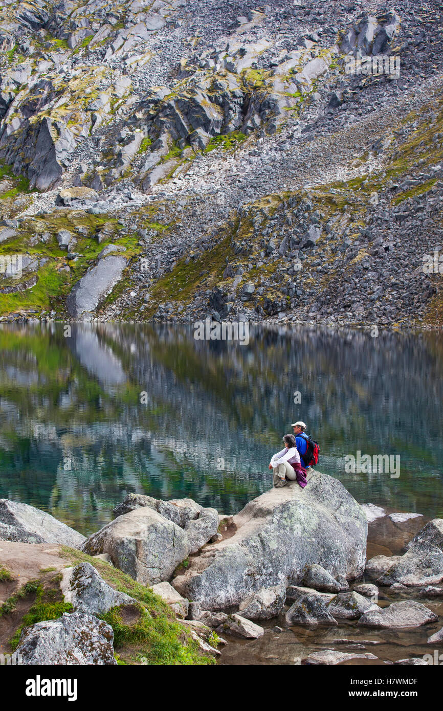 Gli escursionisti seduta su un masso e affacciato sul cavo oro lago in Hatcher Pass centromeridionale, Alaska, STATI UNITI D'AMERICA Foto Stock