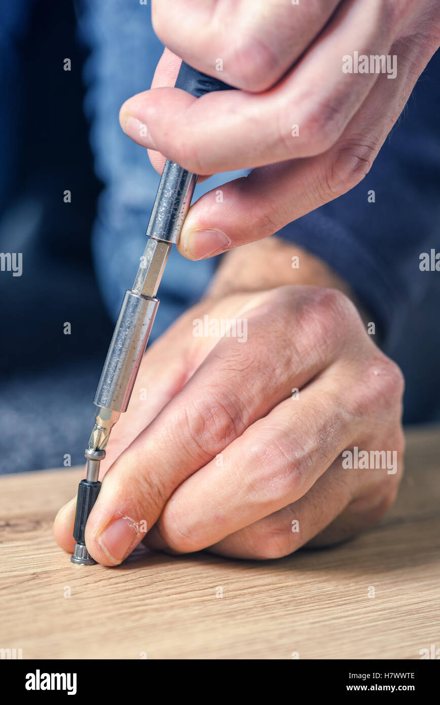 L'uomo assemblaggio di mobili a casa sul pavimento, a mano con un cacciavite Foto Stock