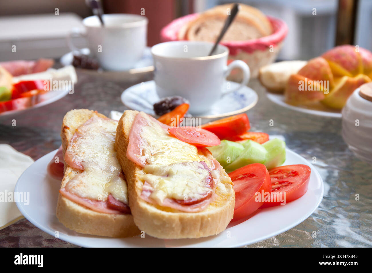 Deliziosa prima colazione sulla terrazza con panini al prosciutto e formaggio caffè e frutta e verdura fresche. Foto Stock