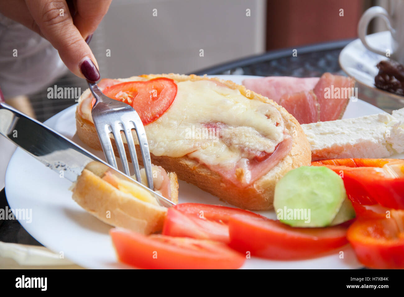 Deliziosa prima colazione sulla terrazza con panini al prosciutto e formaggio caffè e verdure fresche. Foto Stock