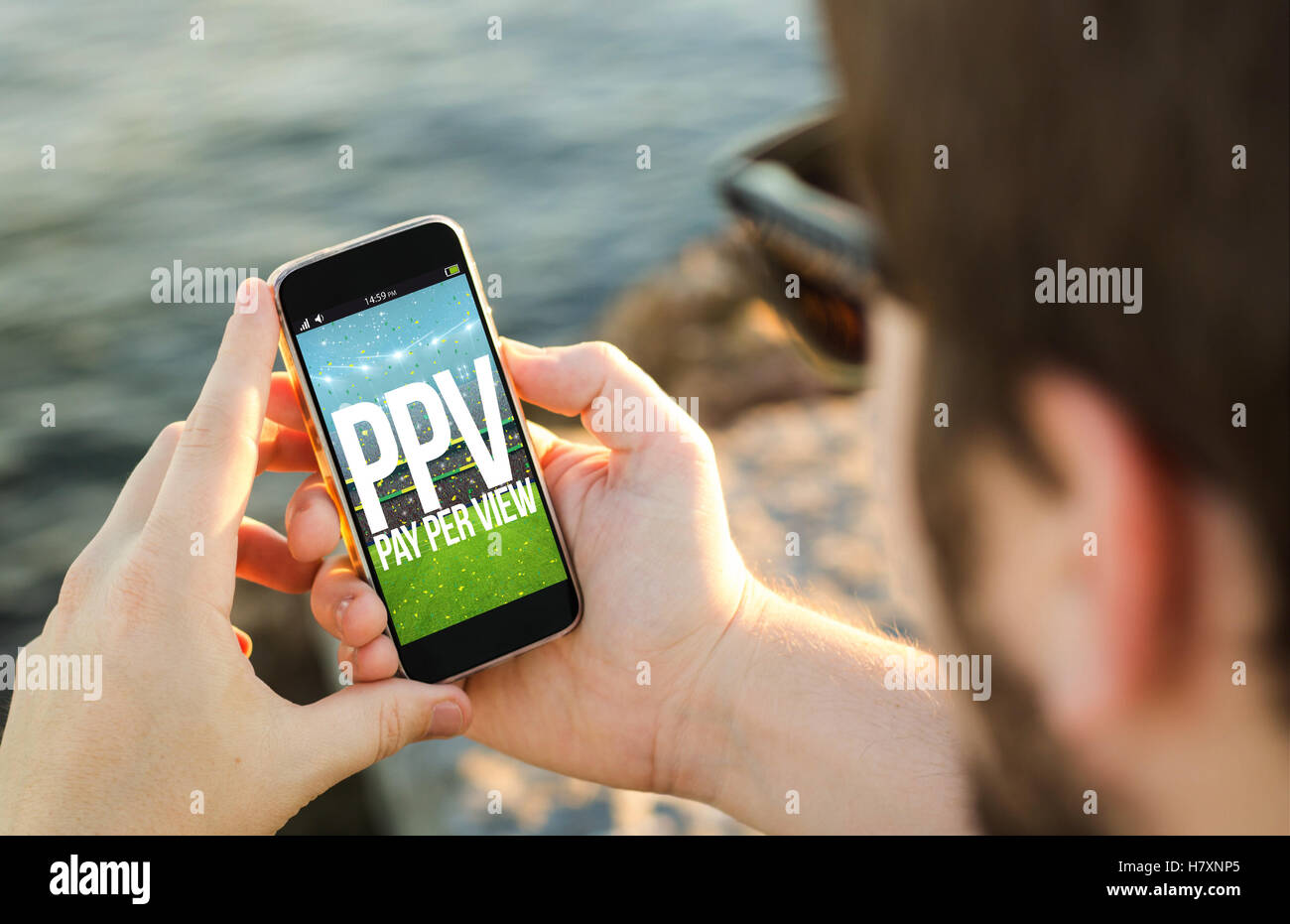 L uomo sulla costa, utilizzando il suo smartphone in montagna con pay per view evento sportivo. Tutti i grafici dello schermo sono costituiti. Foto Stock