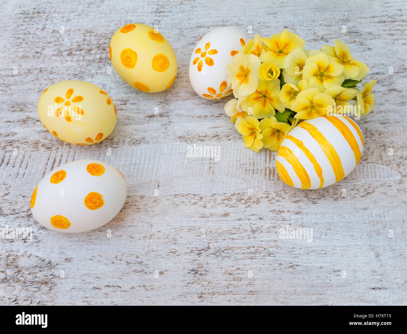 Il bianco e il giallo delle uova di Pasqua decorate da strisce, punti e fiori e primrose bouquet su sfondo bianco Foto Stock