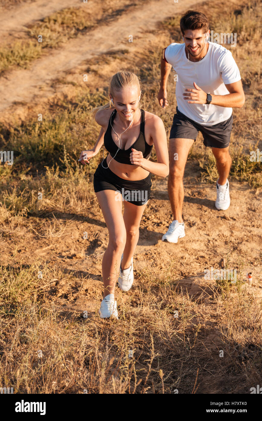 Athletic runner femmina e maschio modello fitness correndo insieme all'aperto Foto Stock