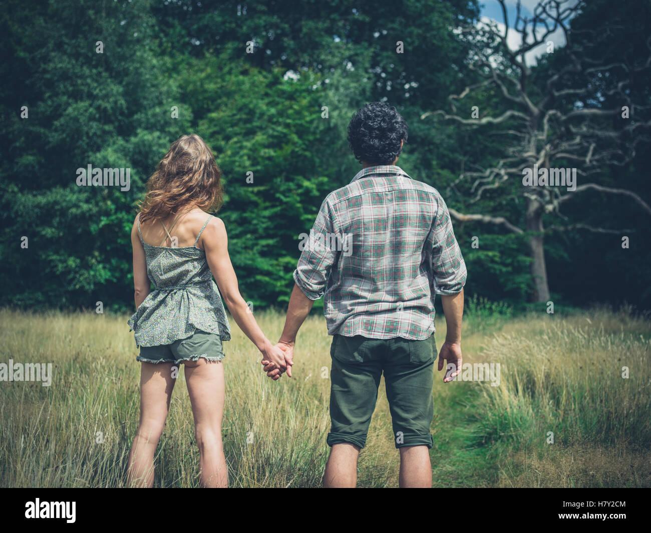 Una giovane coppia è in piedi in un prato nella foresta e tenendo le mani Foto Stock