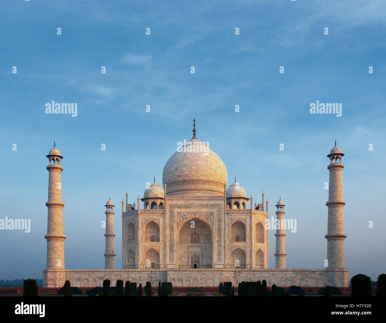 Una bella mattina bagliore arancione sulla parte anteriore facciata in marmo dell'iconico Taj Mahal centrata sotto un calmo mattino cielo blu da telep Foto Stock