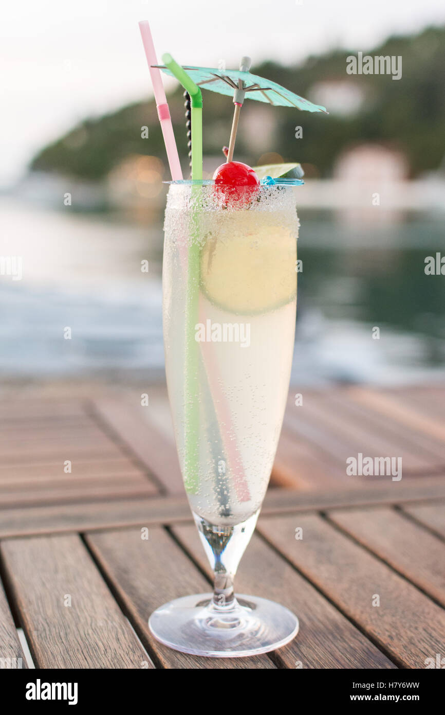 Il Gin Fizz cocktail con zucchero a rim e cannucce di plastica - inizio serata in Lakka, Paxos Grecia, Europa Foto Stock