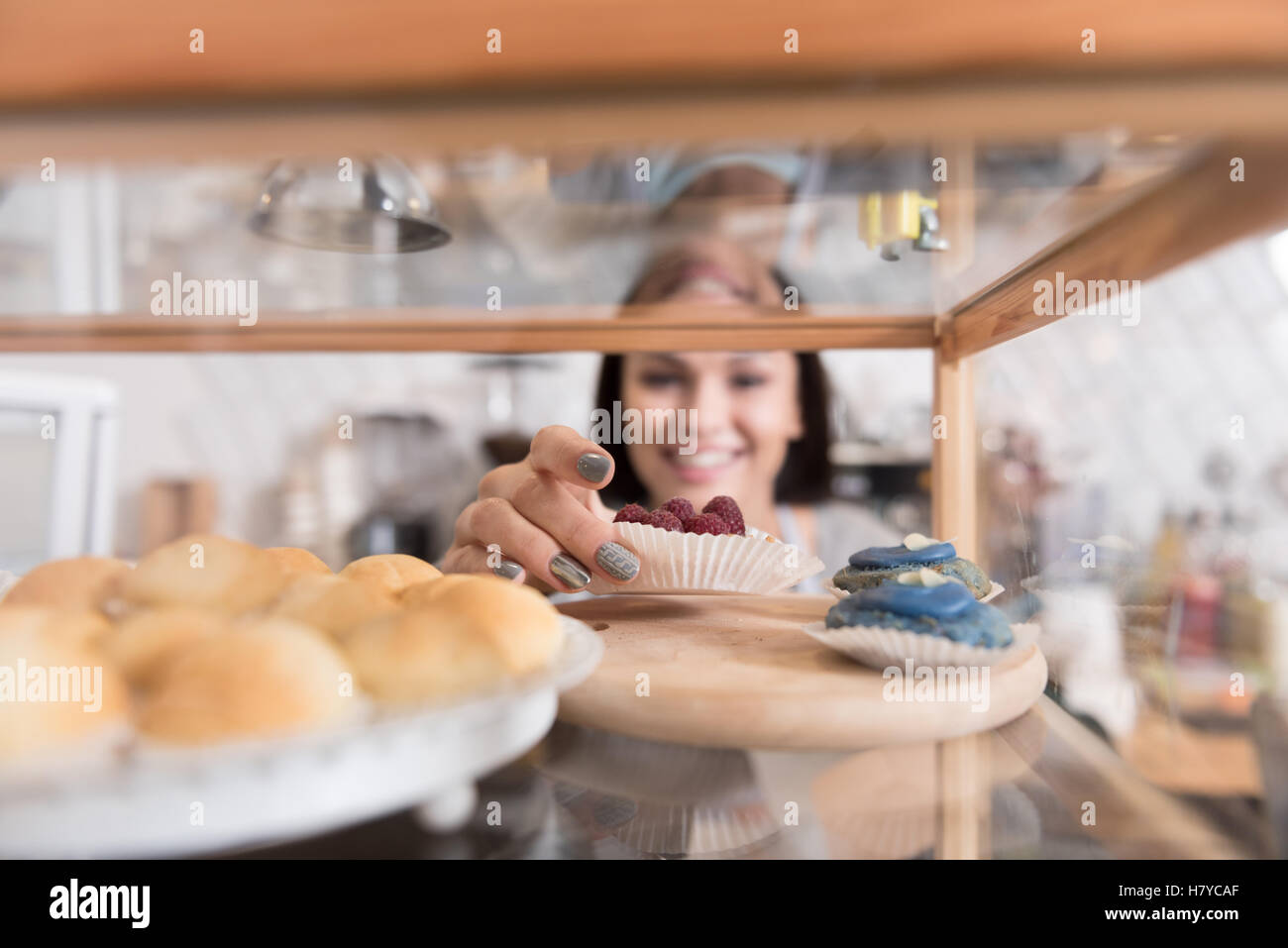 Felice incantevole donna sorridente getting torta dal display stand. Foto Stock