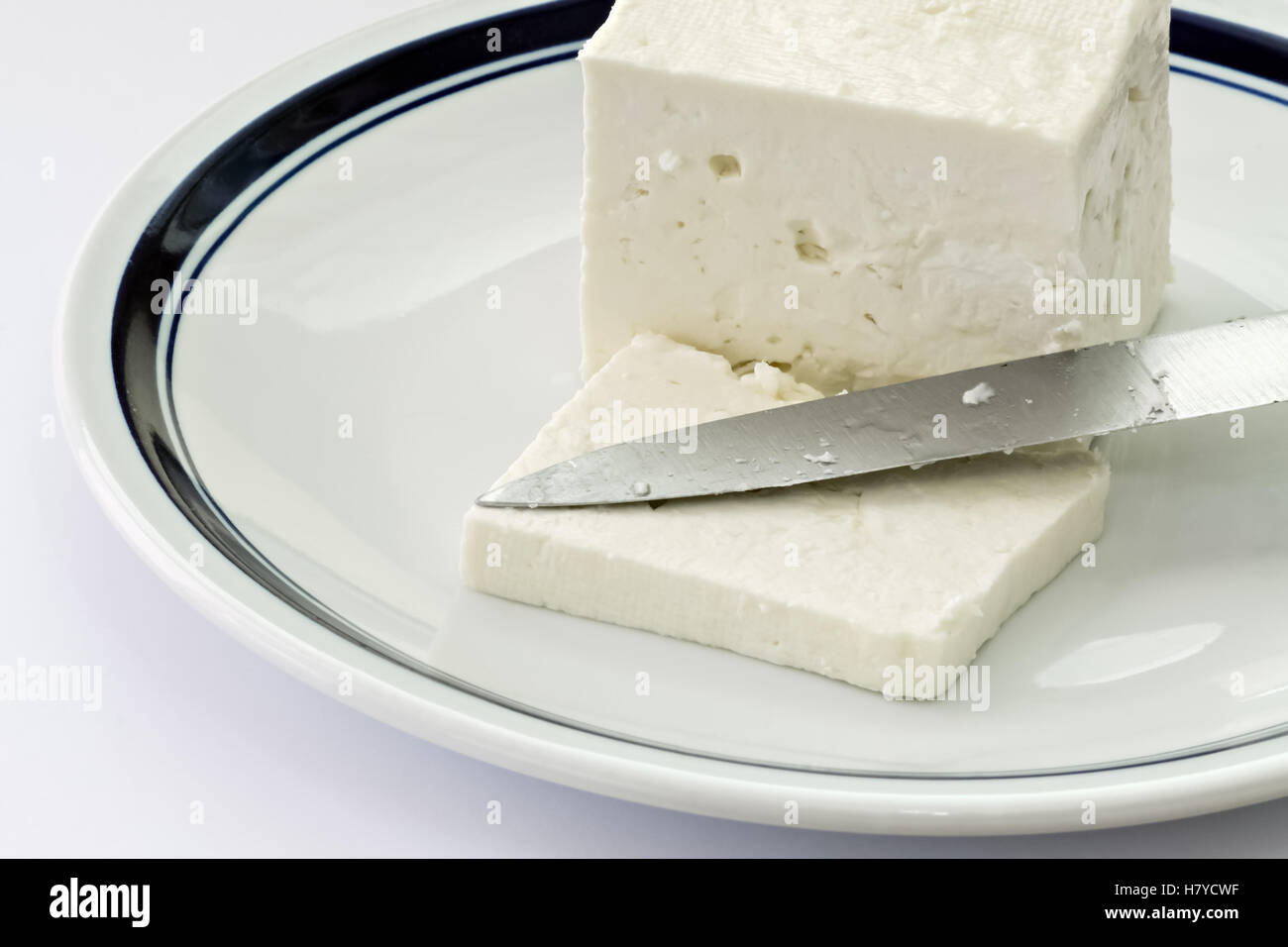 Fetta di formaggio di vacca e il coltello in una piastra bianca Foto Stock