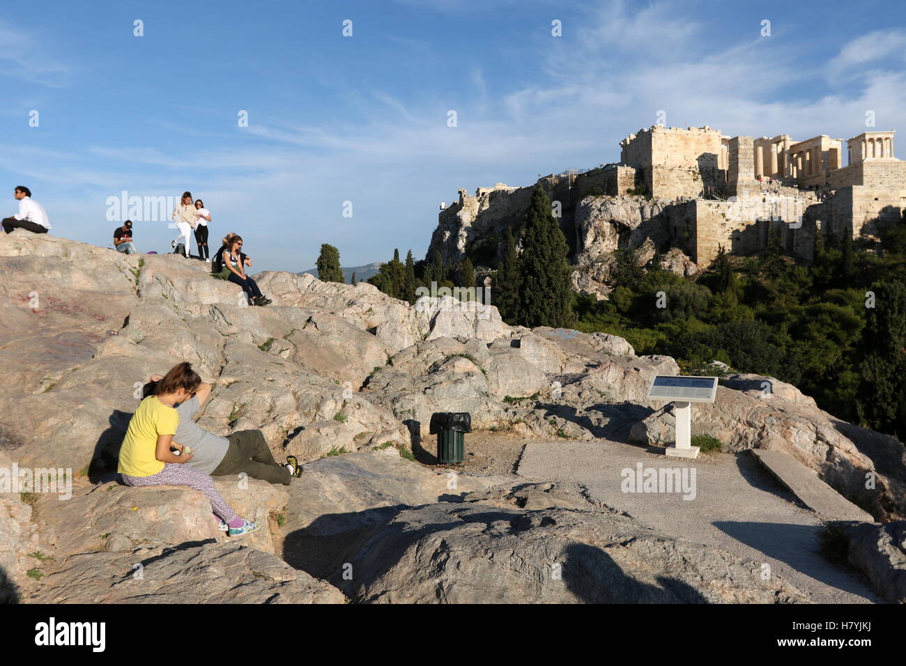 Persone sedute sull Areopago hill, un ruolo di roccia affiorante situato a nordovest dell'Acropoli di Atene, Grecia. Foto Stock