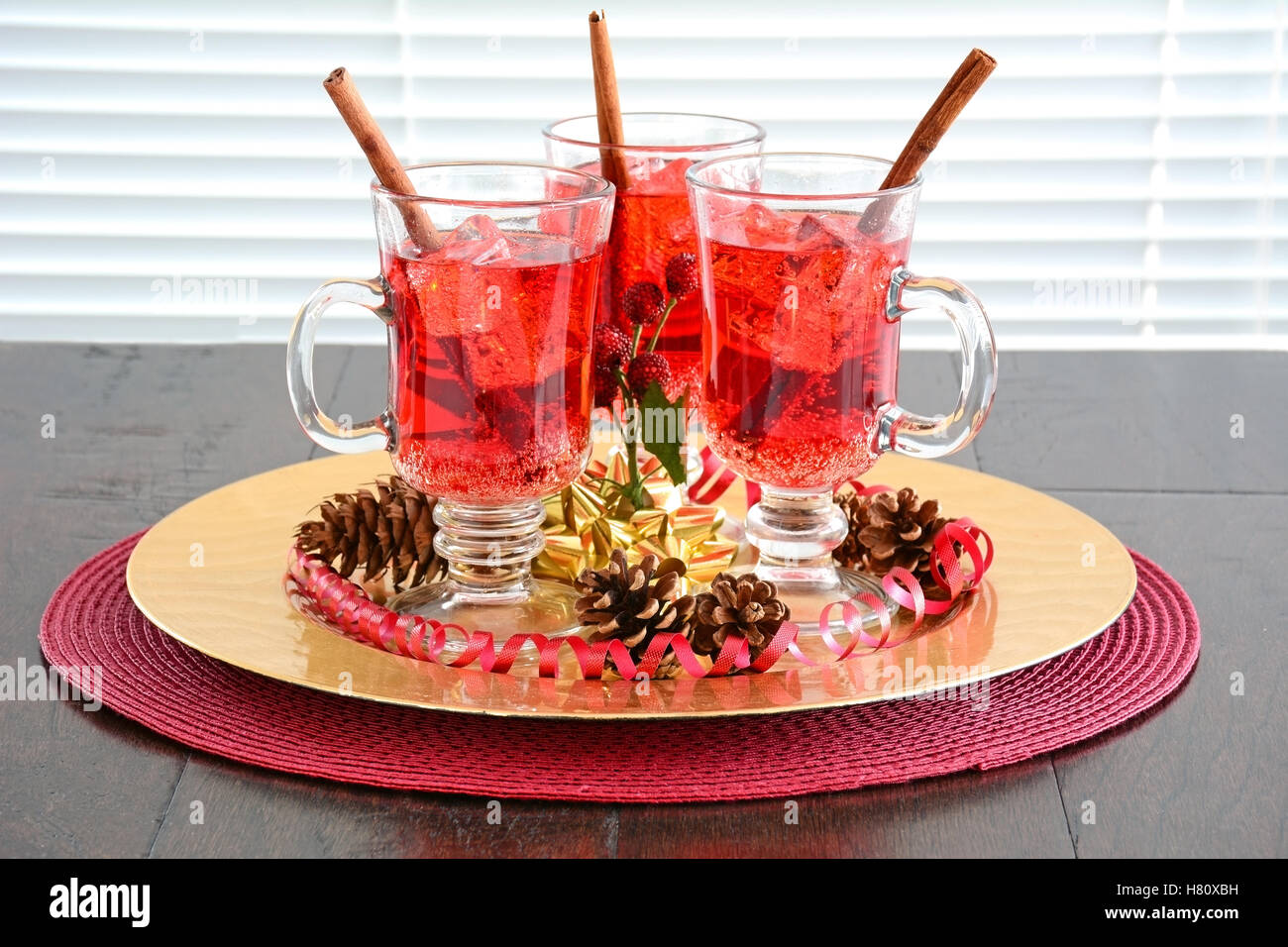 Festive rosso frizzante di soda di mirtillo palustre di bevande con cannella agitare bastoni in rosso e oro accenti a tema. Profondità di campo Foto Stock