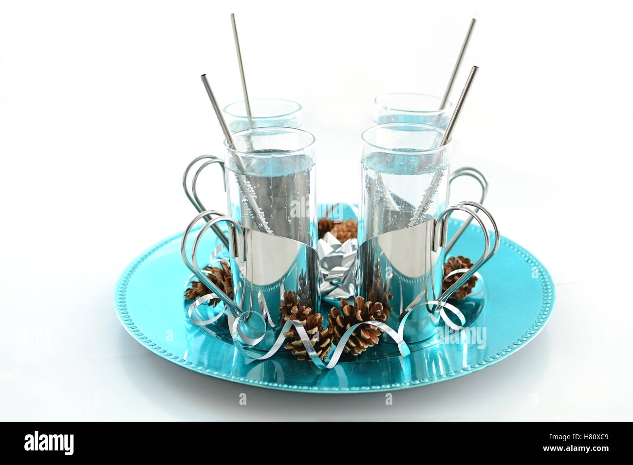 Vini spumanti non caffeinated, soft drink in argento titolari sul vassoio turchese con festosa pigne e nastro argentato riccioli Foto Stock