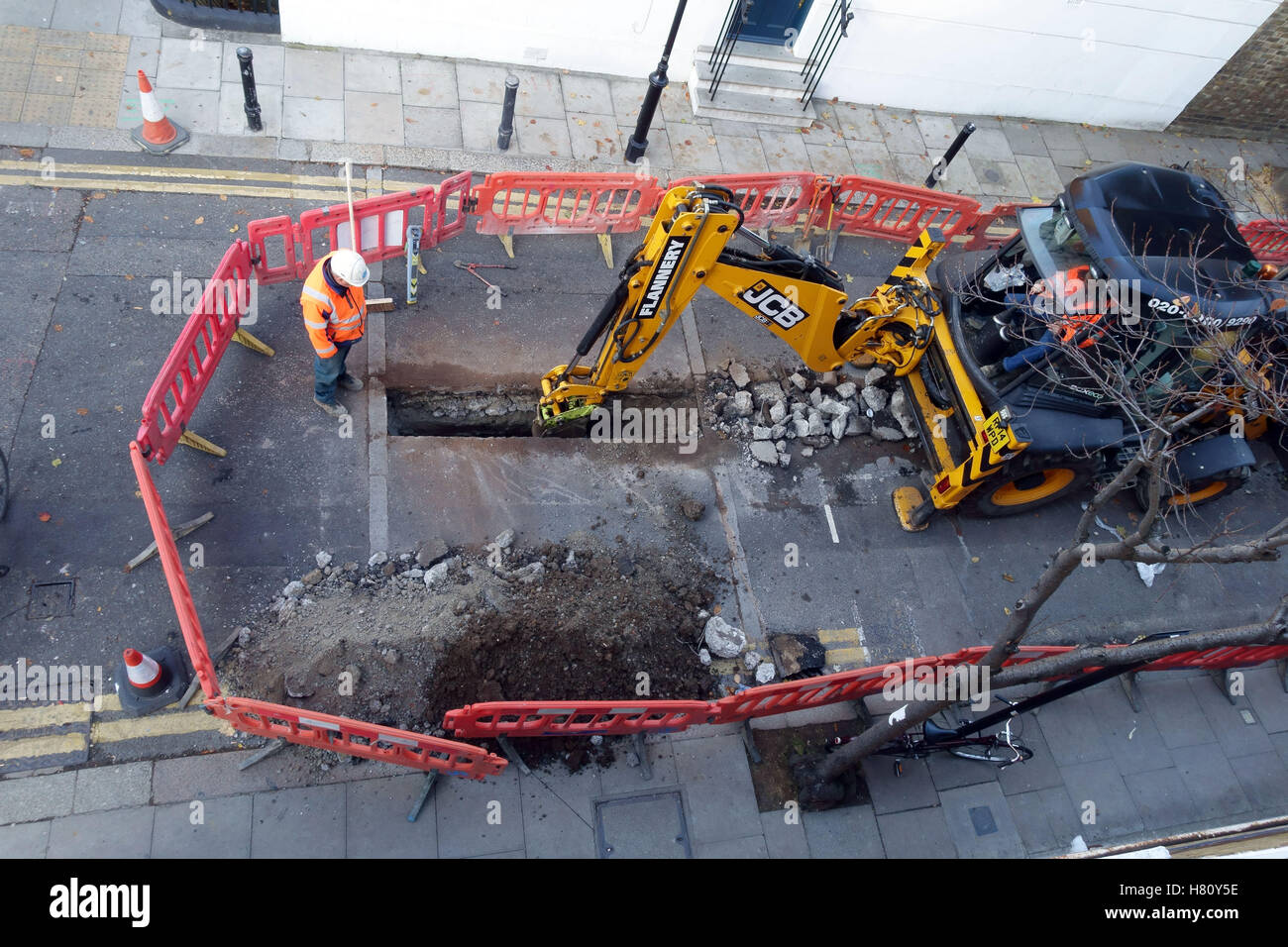 JCB digger scava per lavori stradali in London side Street, Londra Foto Stock
