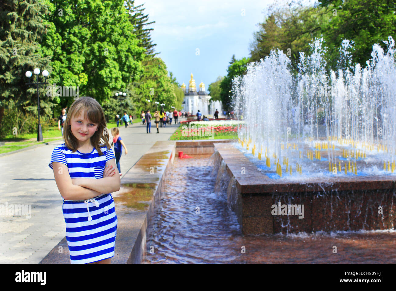 Moderno e giovane ragazza ha un riposo nel parco della città con fontane in primavera Foto Stock