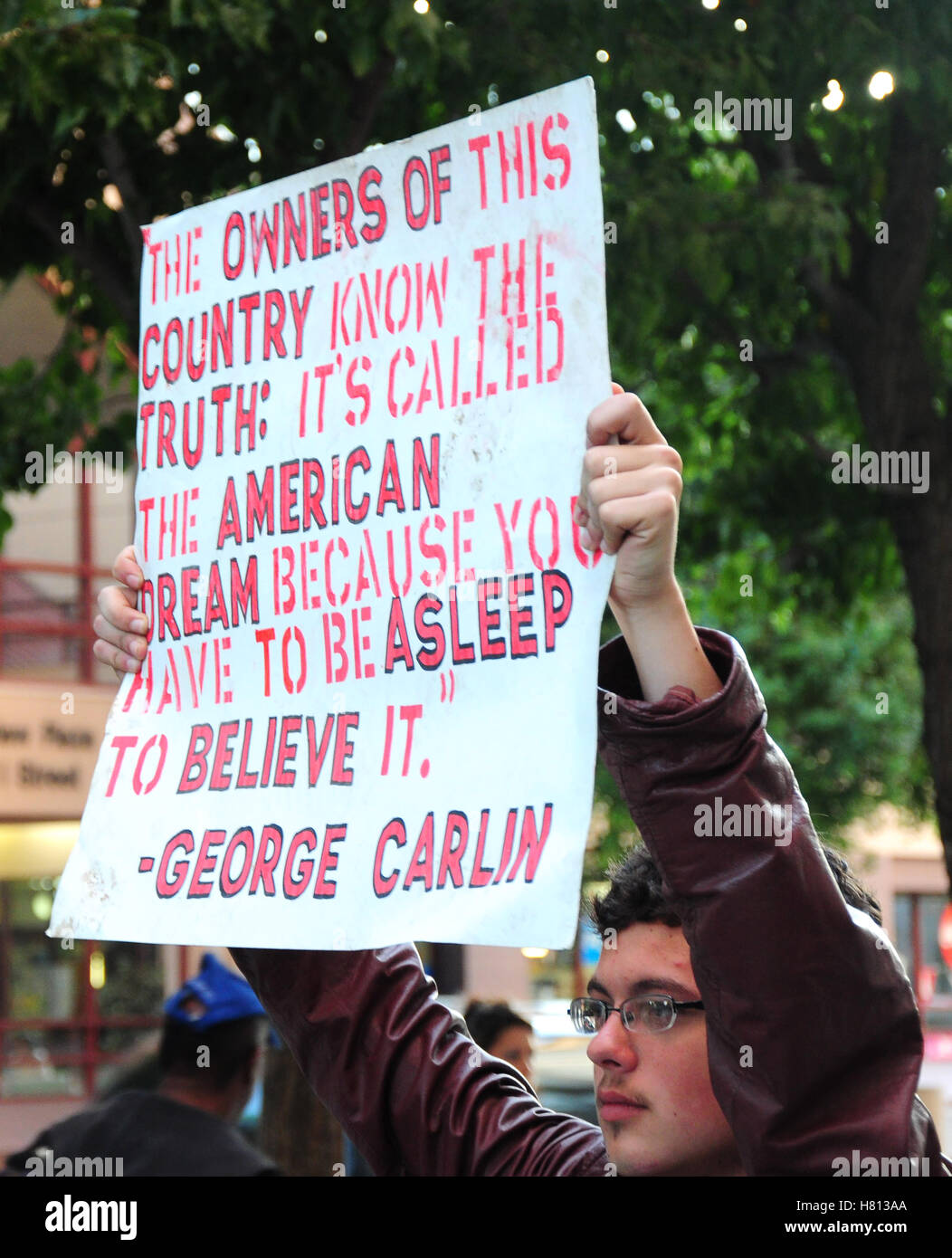 Giovane uomo detiene un segno con un George Carlin preventivo a una protesta a Sacramento, California Foto Stock