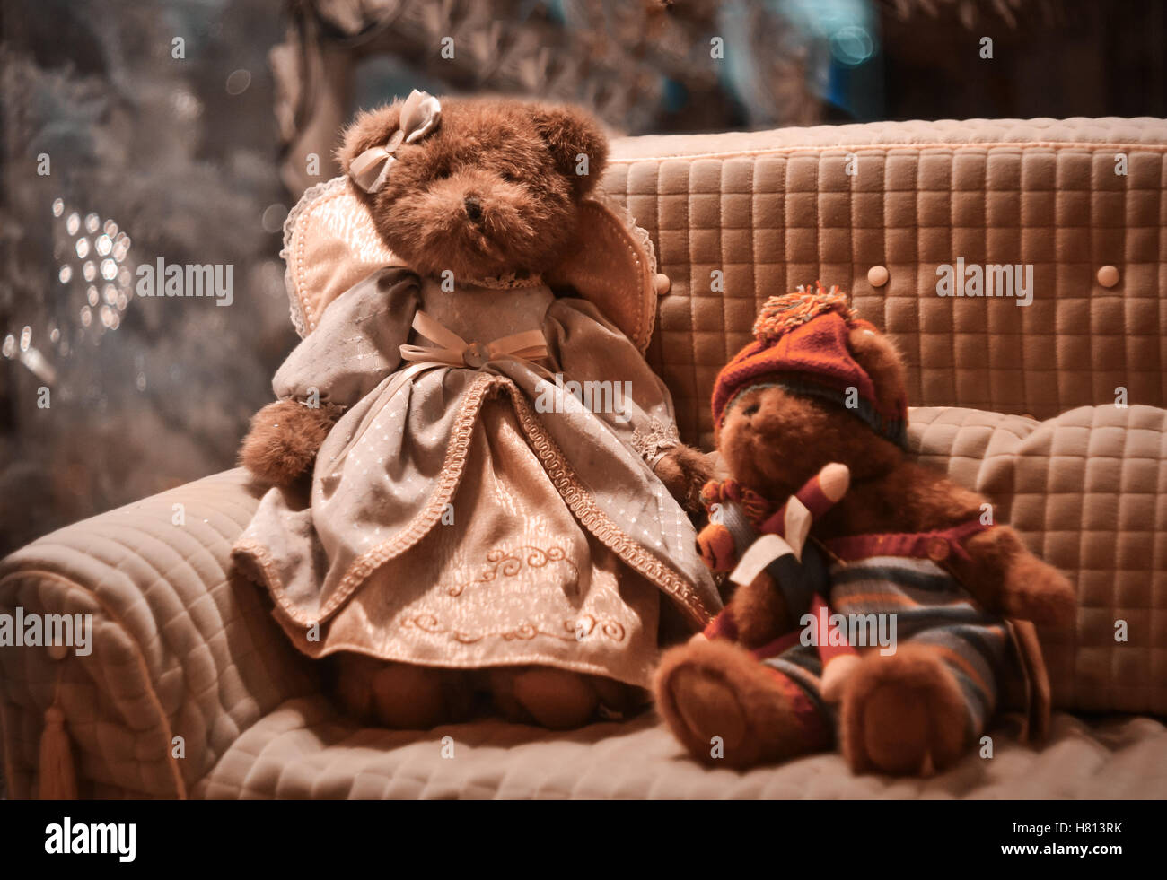 I giocattoli di peluche orsetto nel vestire e il suo amico seduto sul divano vicino a albero di Natale Foto Stock