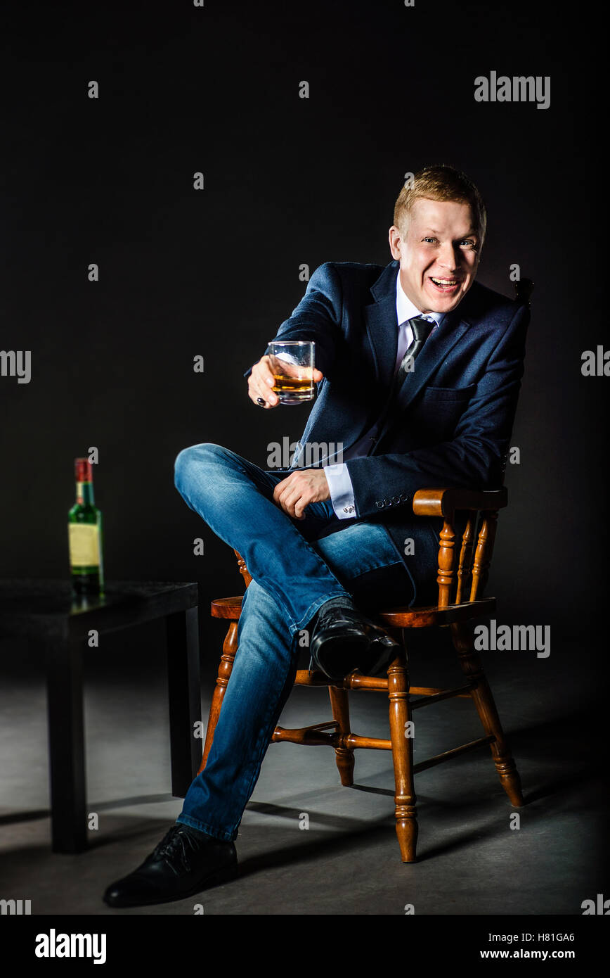 La felice giovane imprenditore offre un bicchiere di whisky e racconta un toast Foto Stock