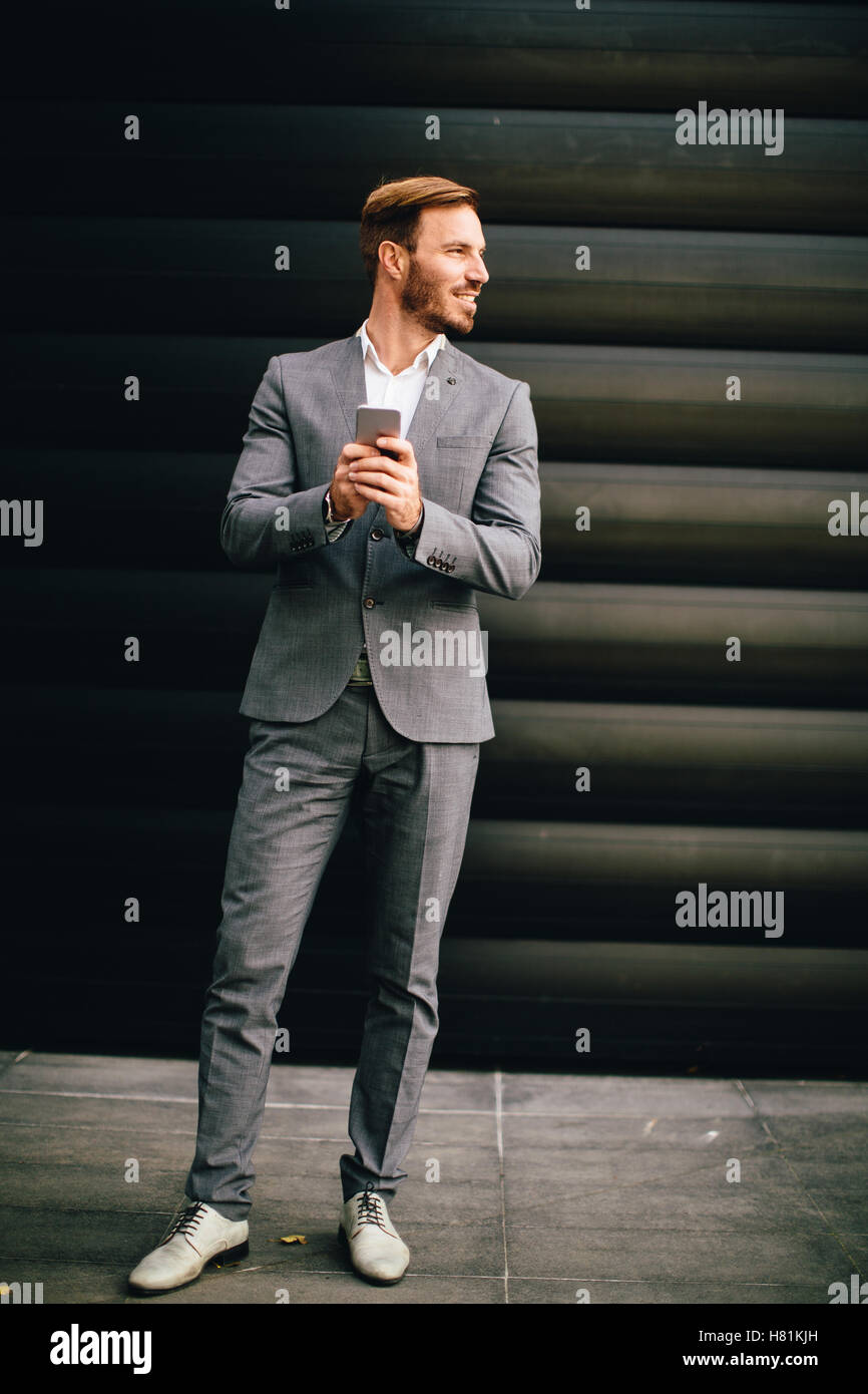 Imprenditore con un telefono dal muro nero Foto Stock