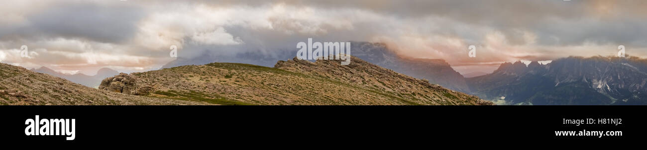 Vista panoramica dal picco di montagna Settsass nelle Dolomiti con calda cloudscapes colorati appesi sulle rocce circostanti Foto Stock
